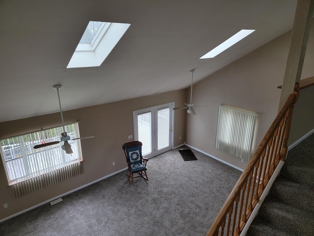 unfurnished room with high vaulted ceiling, ceiling fan, carpet floors, and a skylight