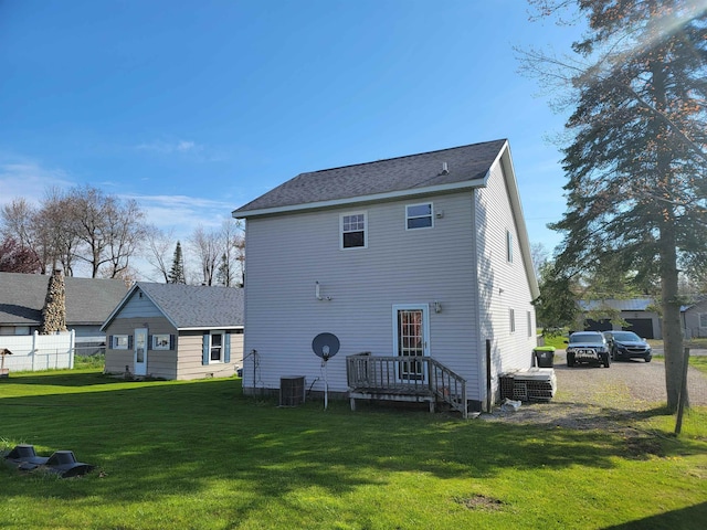 rear view of property featuring central air condition unit and a lawn