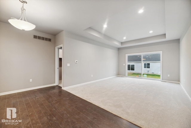 unfurnished living room featuring a tray ceiling and dark hardwood / wood-style floors