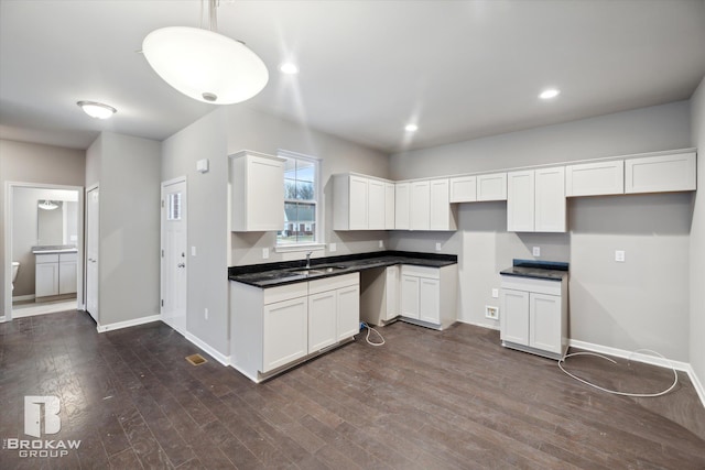 kitchen featuring white cabinetry, hanging light fixtures, and dark wood-type flooring