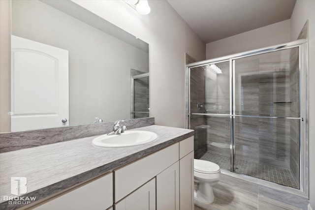 bathroom featuring vanity, toilet, and a shower with door