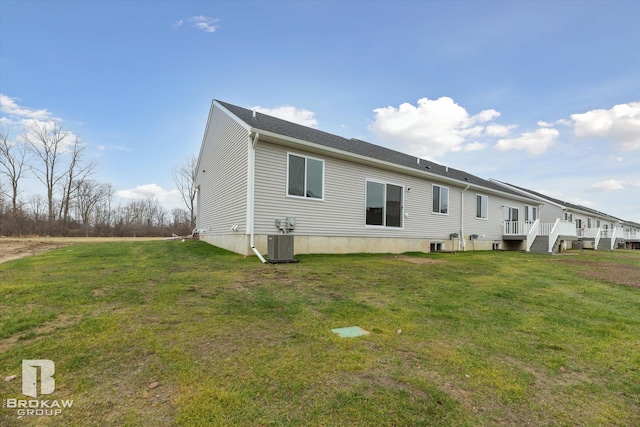 rear view of house featuring a lawn and central air condition unit