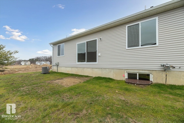 back of property with central air condition unit and a yard