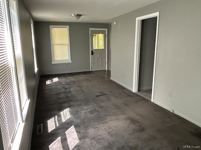 unfurnished room featuring dark colored carpet