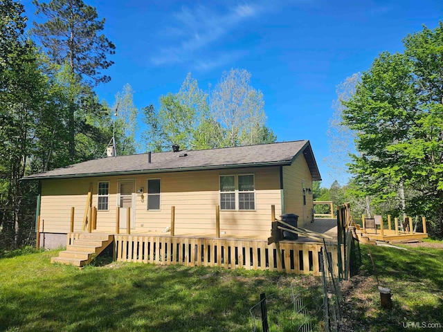 back of house featuring a lawn and a wooden deck