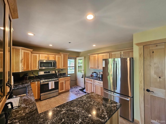 kitchen featuring dark stone countertops, light tile floors, light brown cabinetry, and appliances with stainless steel finishes