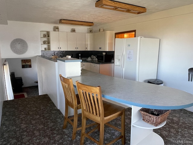 kitchen featuring white refrigerator with ice dispenser, a textured ceiling, and backsplash