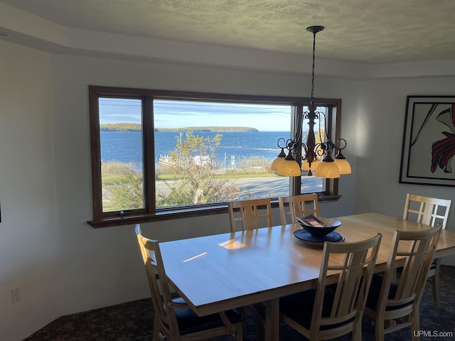 dining room with a healthy amount of sunlight, a water view, and an inviting chandelier