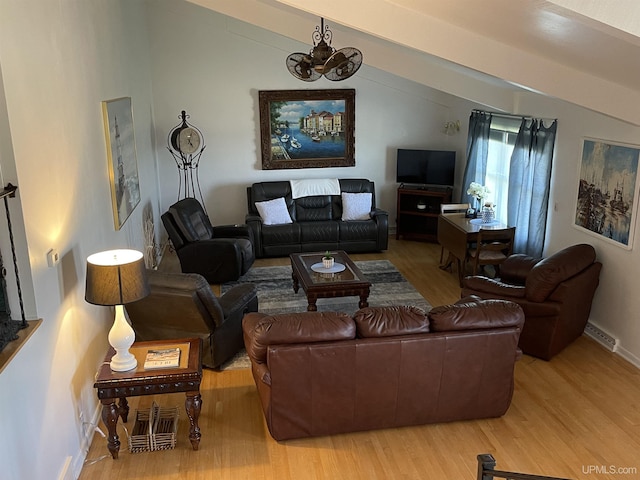 living room with a chandelier, light hardwood / wood-style floors, and vaulted ceiling