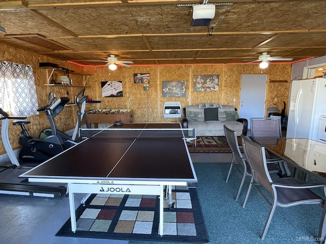 game room with ceiling fan and wood walls