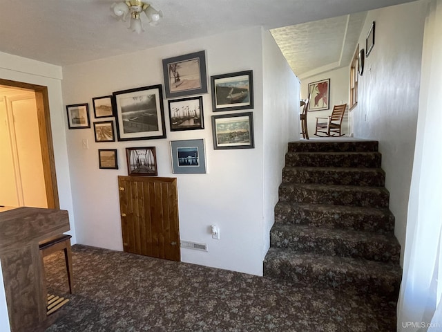 stairs featuring a textured ceiling and carpet floors