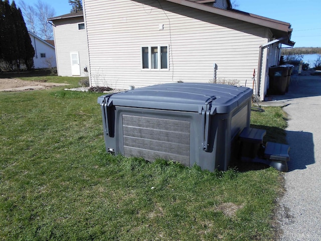 view of home's exterior with a yard and a hot tub