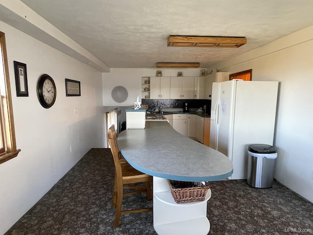 kitchen with backsplash, white fridge with ice dispenser, and a textured ceiling