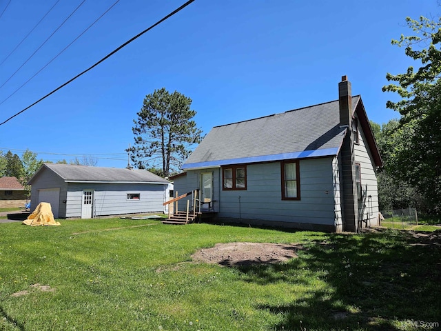 rear view of house featuring a garage, a yard, a chimney, and an outbuilding