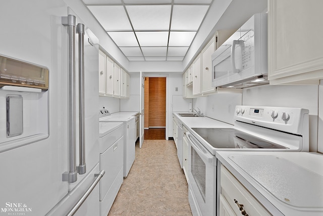 kitchen with white cabinets, a drop ceiling, white appliances, and sink