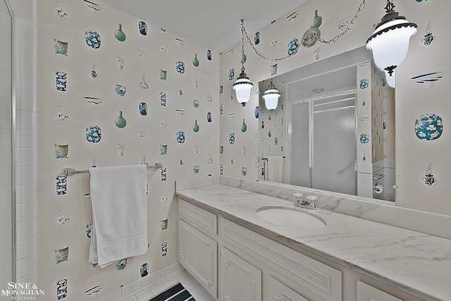 bathroom with a shower with door, vanity, and tile patterned flooring