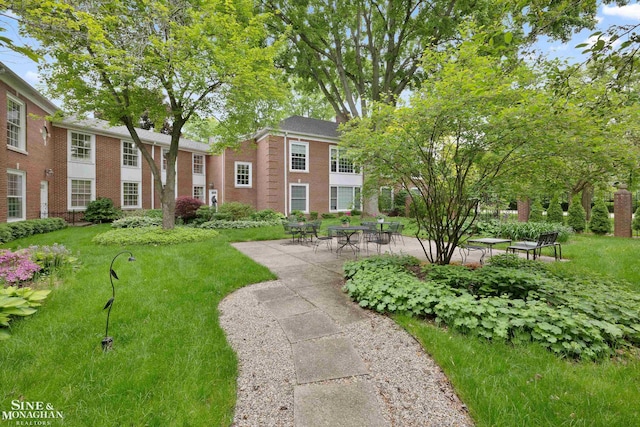 view of property's community featuring a patio and a lawn