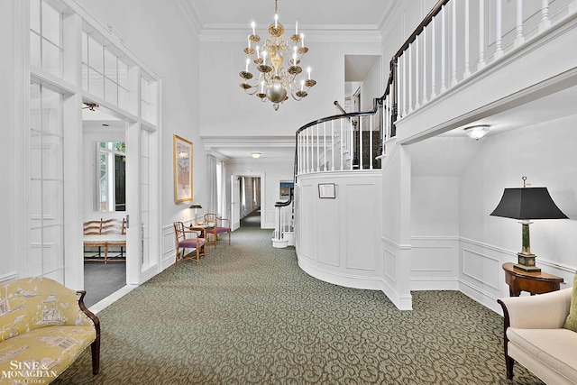 entryway featuring carpet floors, crown molding, a high ceiling, and an inviting chandelier