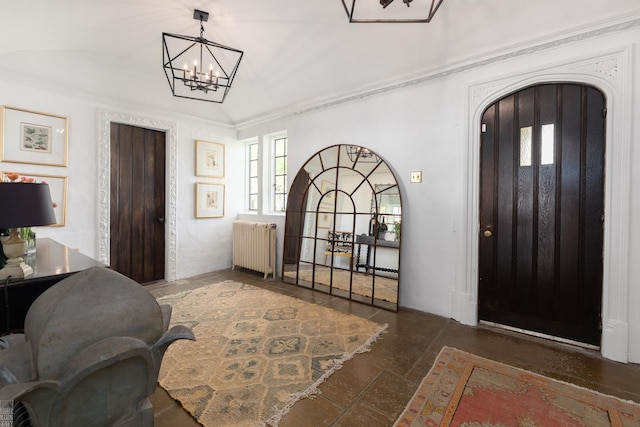 foyer entrance featuring vaulted ceiling, radiator heating unit, arched walkways, and a chandelier