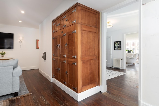 hallway with dark wood-style flooring, radiator heating unit, recessed lighting, and baseboards