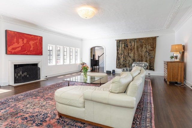 living area with arched walkways, a fireplace, ornamental molding, wood finished floors, and baseboards