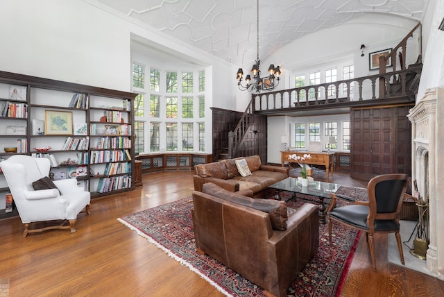 living room featuring hardwood / wood-style flooring, stairway, high vaulted ceiling, and an inviting chandelier