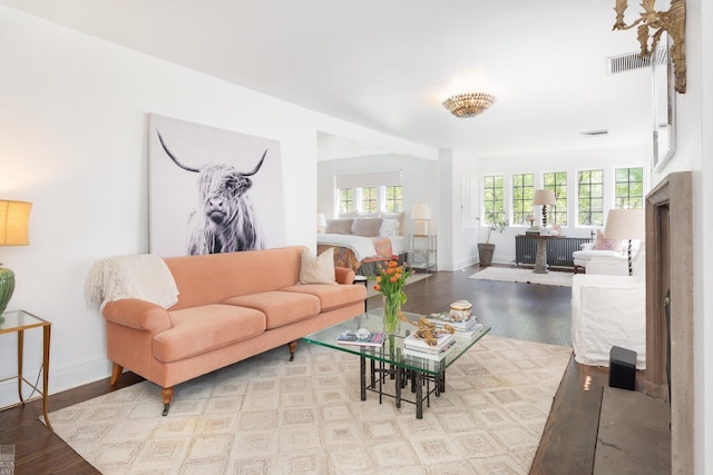 living room with wood finished floors, visible vents, and baseboards