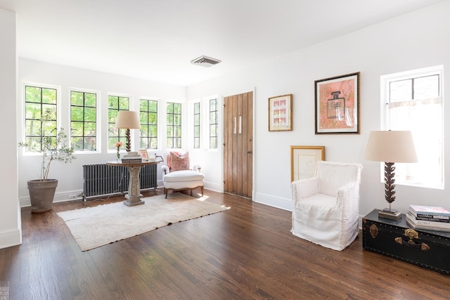 living area with baseboards, radiator heating unit, visible vents, and wood finished floors