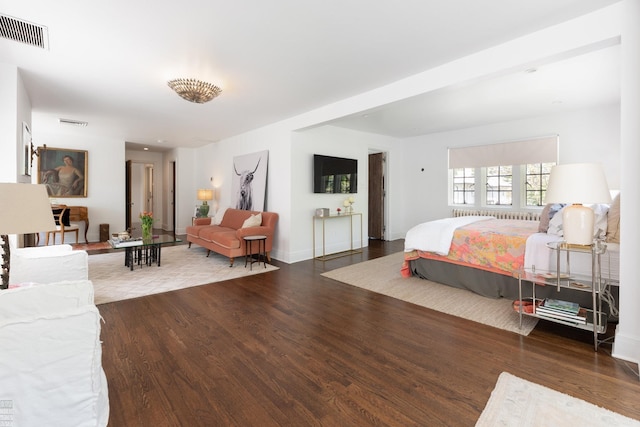 bedroom with baseboards, visible vents, and wood finished floors