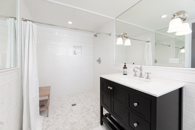 bathroom with vanity, a tile shower, and tile walls