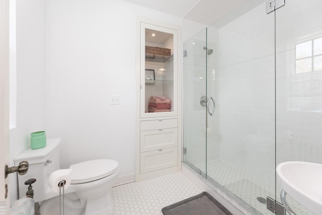 bathroom with a stall shower, baseboards, tile patterned flooring, and toilet