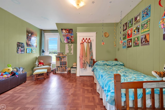 bedroom featuring a closet, wooden walls, and dark parquet floors