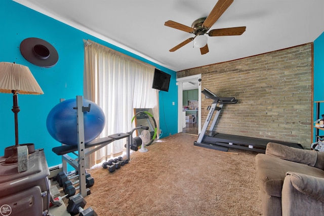 exercise room featuring carpet, ceiling fan, and brick wall