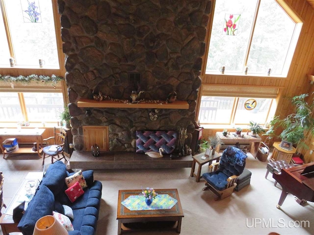 living room featuring a stone fireplace and wood walls