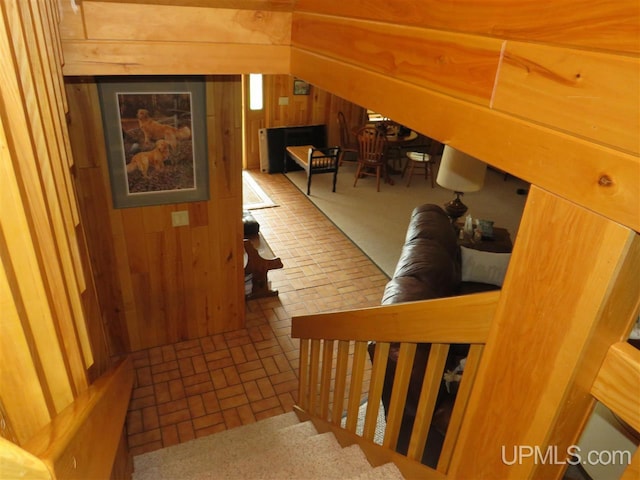 bonus room featuring brick floor, wooden walls, and vaulted ceiling