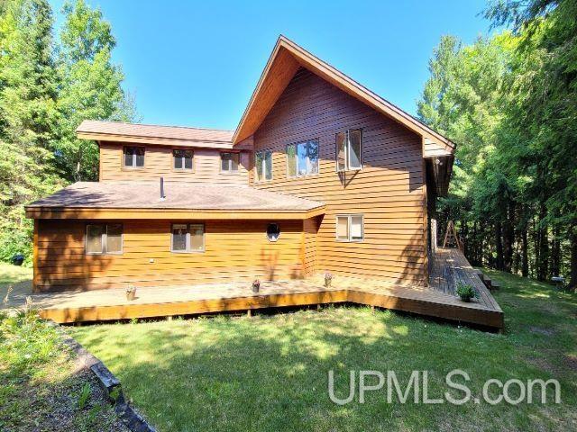rear view of house featuring a lawn and a wooden deck