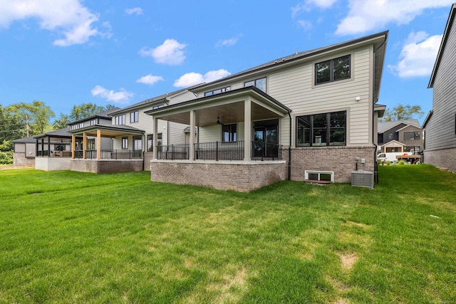 rear view of property with central AC, ceiling fan, and a yard