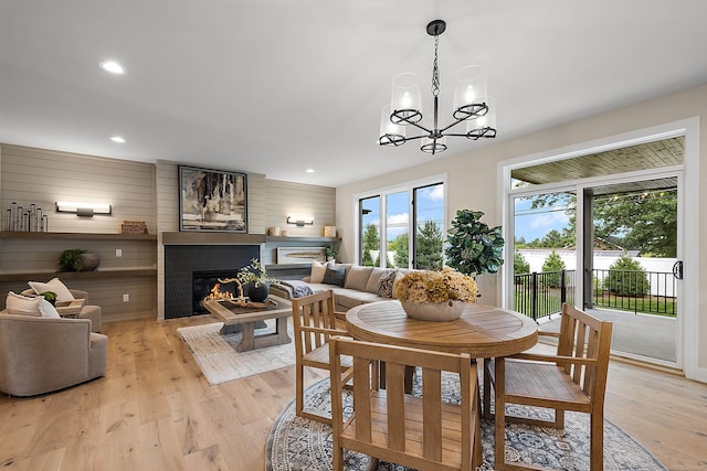 dining area with a chandelier, light hardwood / wood-style flooring, and wood walls