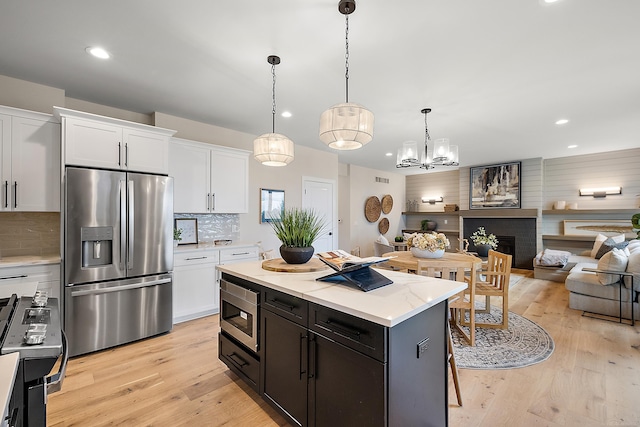 kitchen featuring white cabinets, pendant lighting, stainless steel appliances, and light hardwood / wood-style flooring