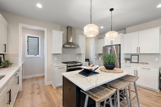 kitchen featuring appliances with stainless steel finishes, tasteful backsplash, wall chimney exhaust hood, light hardwood / wood-style flooring, and white cabinets