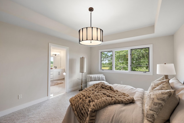 bedroom with a raised ceiling, ensuite bathroom, and carpet floors