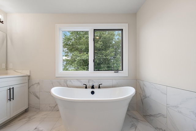 bathroom featuring a washtub, tile walls, and vanity