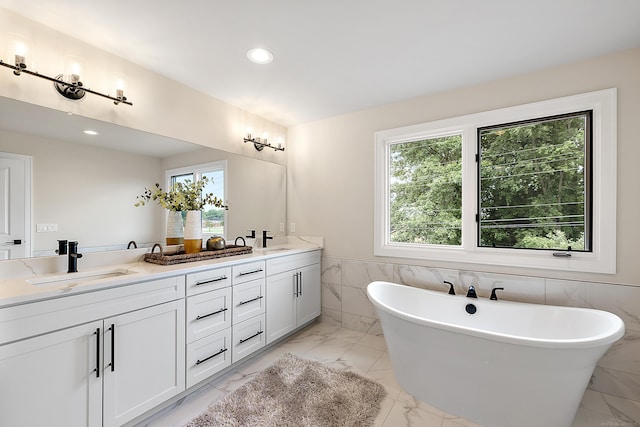 bathroom with vanity, a bathtub, and tile walls