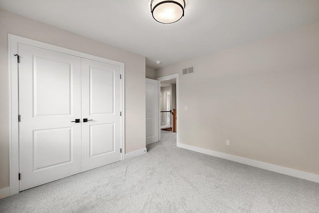 unfurnished bedroom featuring light carpet and a closet