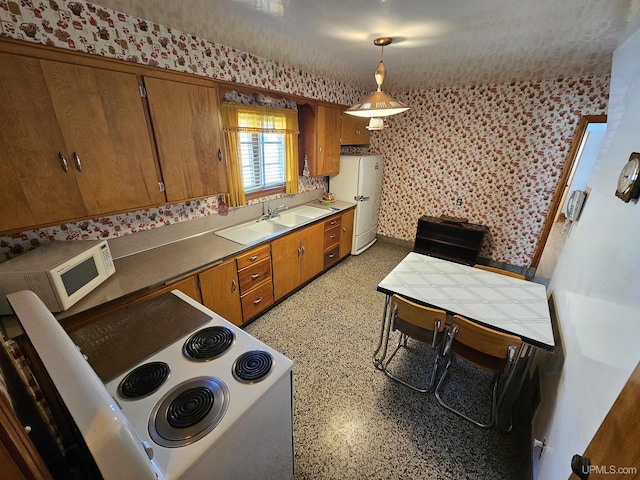 kitchen featuring sink, pendant lighting, and white appliances