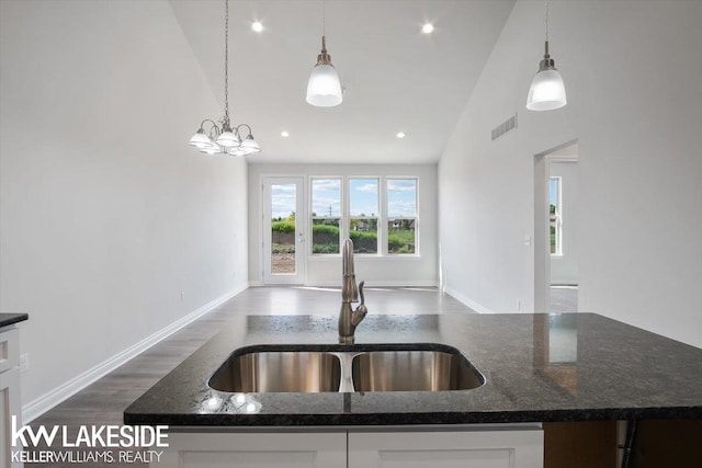 kitchen featuring sink, dark stone countertops, white cabinets, dark hardwood / wood-style flooring, and hanging light fixtures