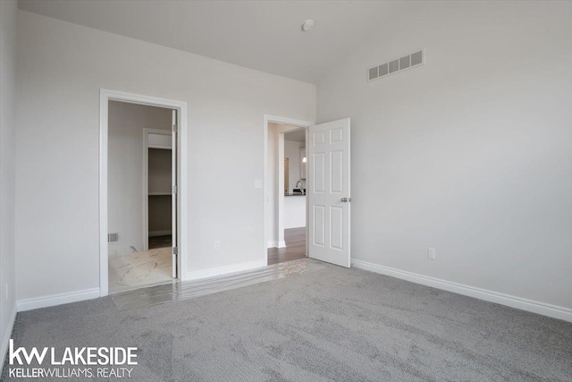 unfurnished bedroom with a spacious closet, vaulted ceiling, and light colored carpet