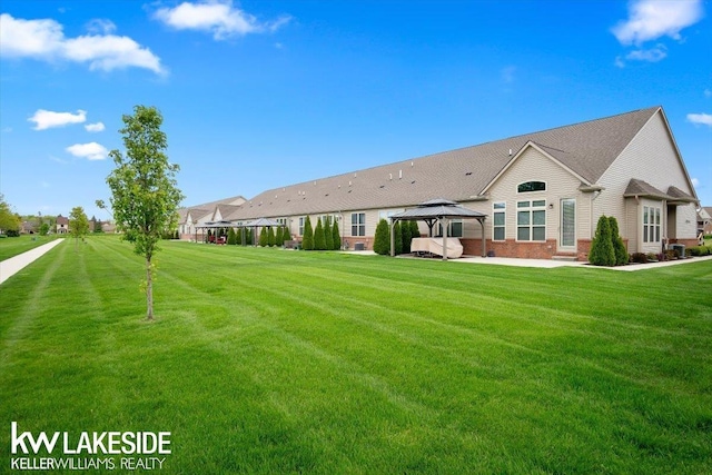 back of property featuring a gazebo and a yard