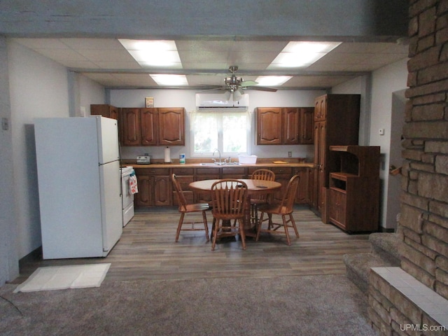 kitchen featuring a wall mounted air conditioner, white appliances, sink, ceiling fan, and light wood-type flooring