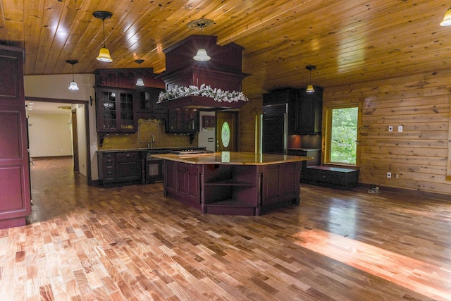 kitchen featuring a kitchen island, wooden walls, hardwood / wood-style floors, wood ceiling, and vaulted ceiling